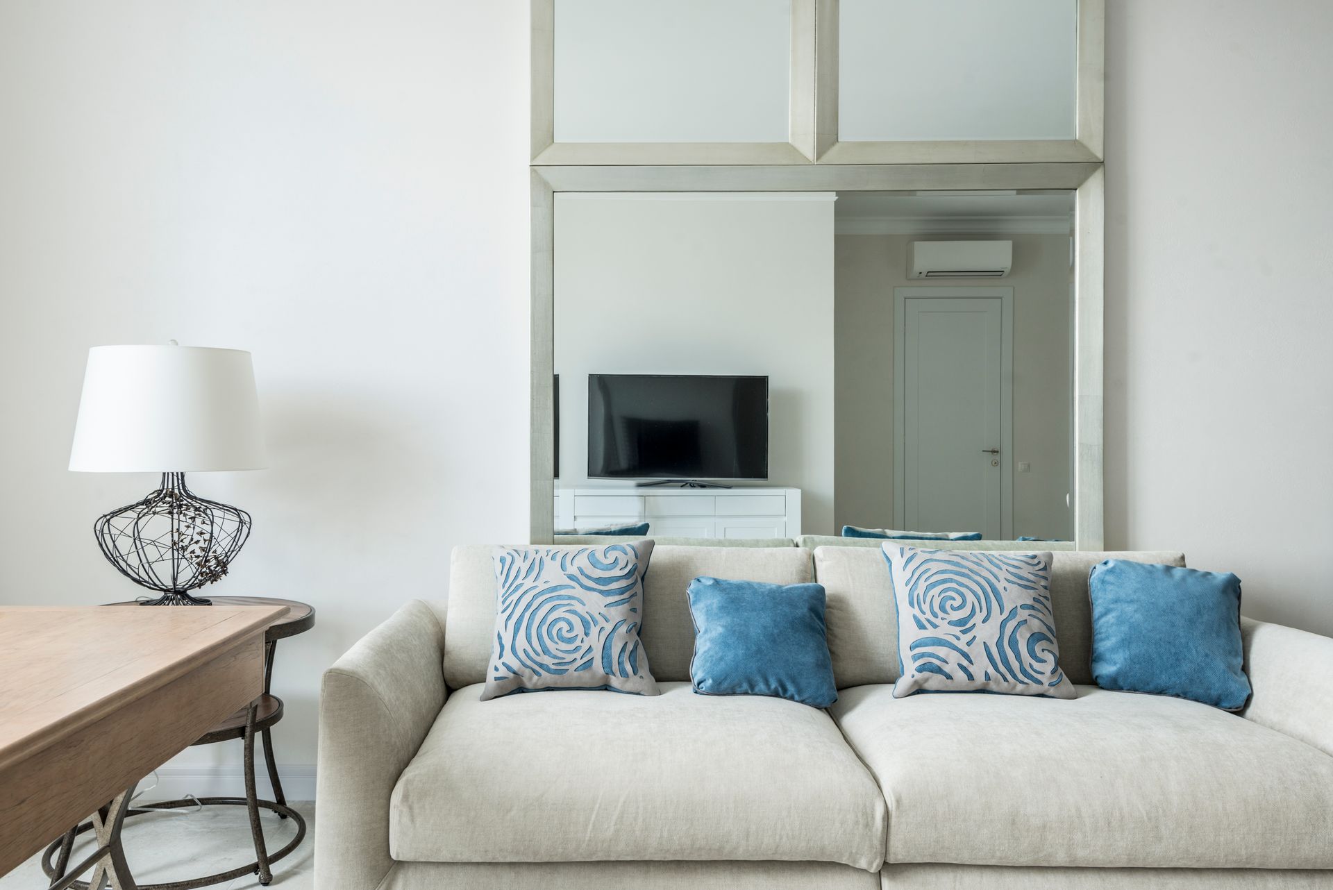 A couch with blue throw pillows in a bright living room